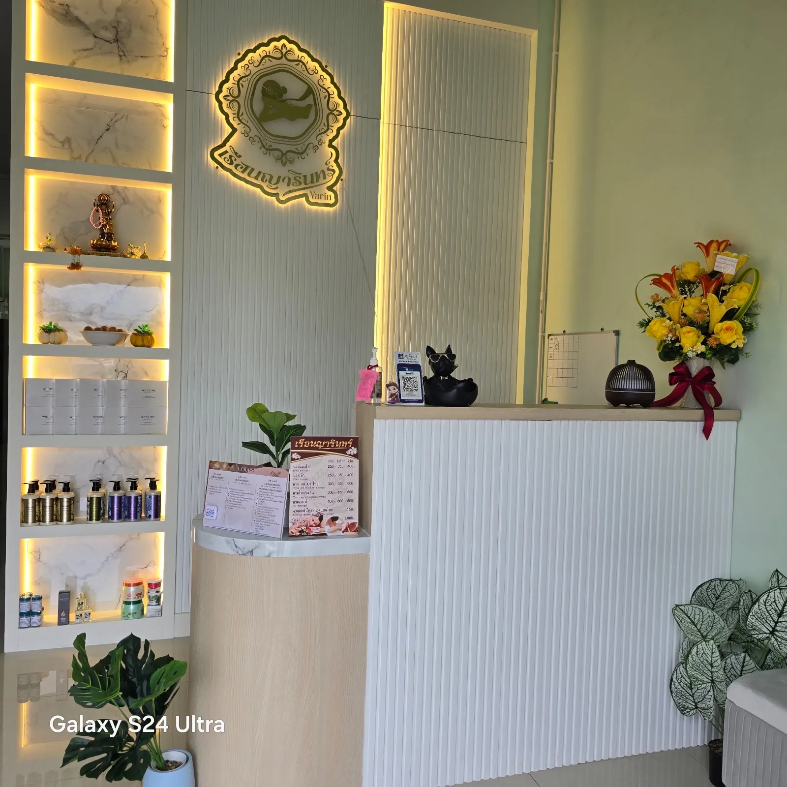 เคาน์เตอร์ต้อนรับร้านเรือนญารินทร์ มีป้ายโลโก้ไฟสีทองบนผนัง